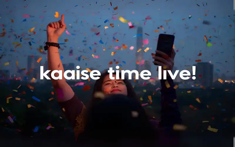 Young people celebrating with a smartphone in hand, Dhaka skyline in the background, confetti and glowing screen suggest winning. Overlay text “kaise time live”